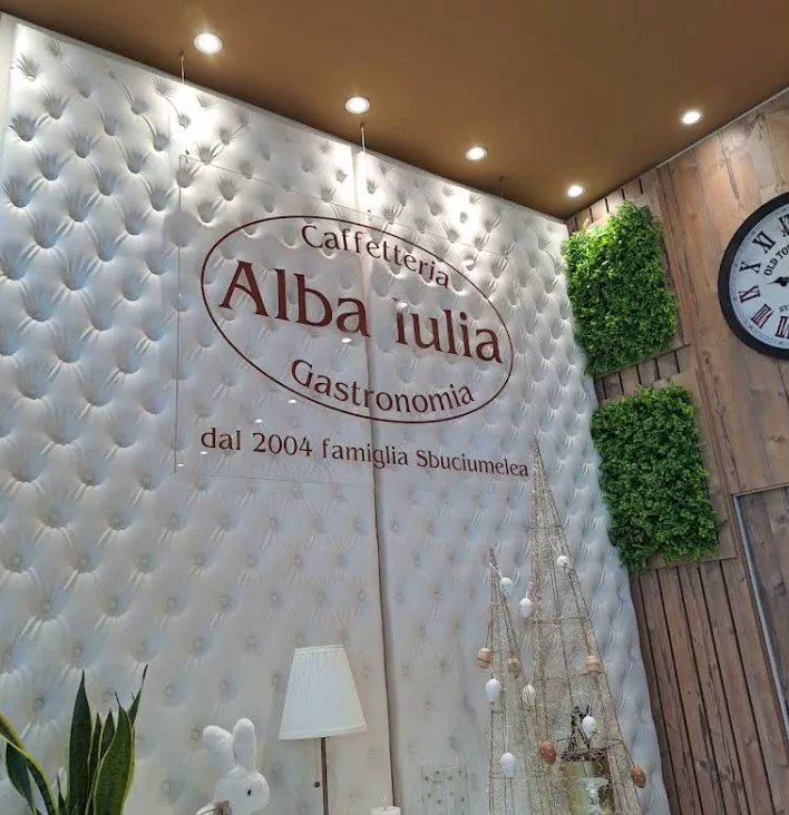 L'insegna ovale sulla parete capitonné: Caffetteria Alba Iulia Gastronomia, dal 2004 famiglia Sbuciumelea